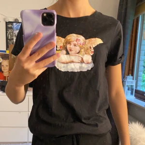 T-shirt  - En svart t-shirt med ett ängeltryck. Storlek XS. Frakten är inräknat i priset 