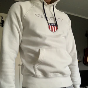 Vit Gant Hoodie Broderat Tryck - Storlek M, passar mig precis då jag är 189cm lång.  Rekommenderas starkt för folk som är 175-185cm. Köpt på NK för 1200kr för två sommar sedan. Använd runt 10 gånger så den är i gott skick! 