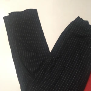 Kritstrecksrandiga kostymbyxor - Raka kritstrecksrandiga kostymbyxor från weekday, i lite tjockare material. Syns inte på bilderna men dom har gylf också. Liten snygg slits längst ner på benen.