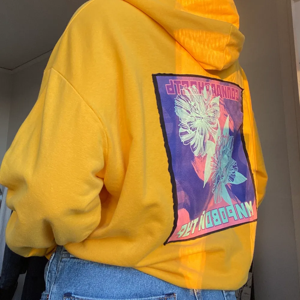 En gul urban outfitters hoodie men tryck på framsidan och en bild på ryggen, har inte använt den mycket men den har två fläckar längst ner på magen . Tröjor & Koftor.