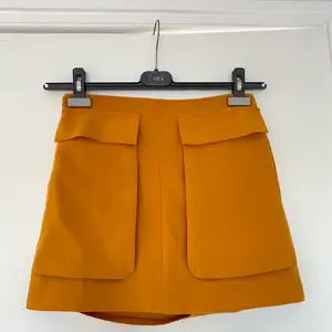 Orange kjol med stora fickor framtill. Använd men i bra skick!! Storlek S men passar XS/S