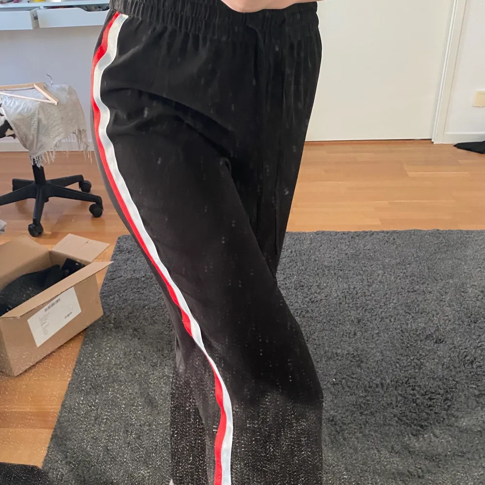 Coola svarta byxor som är jättesköna från Gina. De har vit röda sträck på båda sidorna av benen och snöre runt midjan så man kan justera storleken. . Jeans & Byxor.
