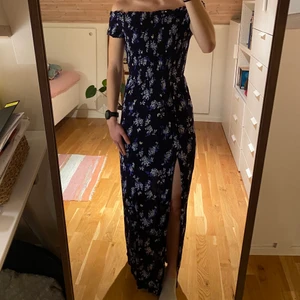 Blå mönstrad långklänning - Offshoulder långklänning i blått blommönster, slits på höger ben. Strl 34, jag är 165cm lång. 