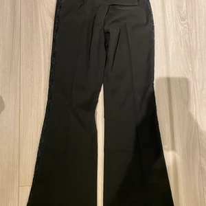 Svarta kostymbyxor med spets - Ett par svarta kostymbyxor med spets på sidorna från Night Queen. Super fina enkla kostymbyxor men som sticker ut i mängden! Byxorna är ganska lågmidjade och tyvärr för små för mig vilket göra att det inte är möjligt för mig att skicka en bild när de sitter på tyvärr. Byxorna är i storlek 38!