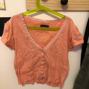 Superfin croppad tröja med spets detaljer,lite urringad och lite puffiga ärmar. Den ser persiko färgad ut på bilden men är mer åt det rosa hållet:)