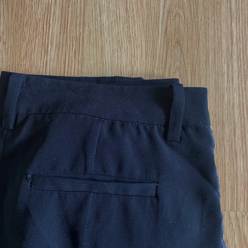 Svarta kostymbyxor med fin detalj!  Kostymbyxor från Forever 21, köpta i USA. Fin detalj längs sidorna i silkesliknande material. Med bälteshällor, fickor framtill och fejkfickor baktill.   Välanvända men mycket kvar att ge!   Material: 100% polyester   Köparen betalar frakten☀️. Jeans & Byxor.
