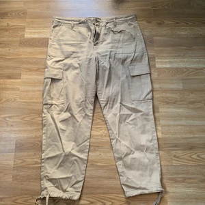 Cargo pants - Säljer ett par skitsnygga beiga cargopants i storleken 42! Dessa byxor går även att justera längst ner efter önskemål. Säljs pågrund av fel storlek! 