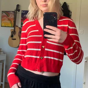 Röd button-up från Monki stl.S - Röd/vit button-up från Monki! Denna koftan är riktigt härlig och ger mycket färg i vardagen. Den är röd med vita ränder och har även knappar i färgen rose-gold. Knapparna är formade som hjärtan! Denna koftan är superbekväm och passar väldigt bra på kroppen! Storleken är S och den går att matcha med t.ex ett par svarta kostymbyxor och röda eller vita skor! Jag älskar detta plagget men väljer att sälja då jag inte använder det så ofta! 🥰