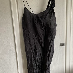 Acne svart foderlänning - Retro klänning från acne med ett slätat och ett strapband. Den är i ett foderliknande tyg. Ett mindje band medföljer.