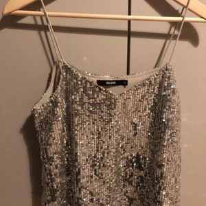Plajettopp från bikbok  - Säljer denna festliga topp ifrån bikbok. Den är i storlek XS men passar även mig som har S. Täckt med silvriga paljetter, är v-ringad  och har spagettistraps. Super fint skick. Frakten ingår i priset. Hör av dig vid intresse eller frågor :)