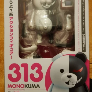 Monokuma Actionfigur - Säljer en cool Monokuma actionfigur från Super Danganronpa 2. Den är vit och svart med ett stort grin och röd öga på den svarta sidan. Perfekt för samlare eller fans av serien! Figuren är i originalförpackning med japansk text och varningsetikett. Ett måste för alla Danganronpa-fans!
