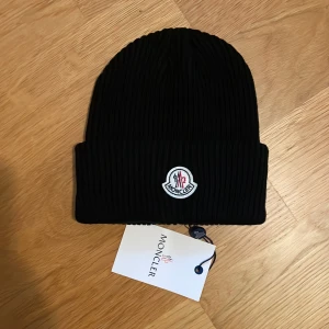 Ny Moncler liknande mössa Beanie mössa snygg modern och populär Svart färg.  - Moncler liknande möss i beanie modell. Snygg, populär, modern och klassisk. Svart. Passar till allt.  One Size