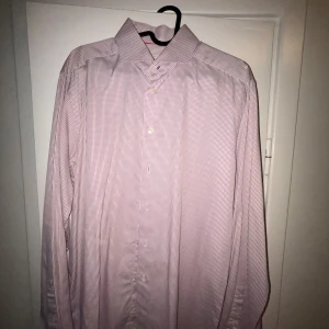 Rutig skjorta från Eton - Säljer en stilren rutig skjorta från Eton i rött och vitt. Skjortan är långärmad och har en klassisk krage med knappar. Perfekt för både kontoret och mer avslappnade tillfällen. Passar bra till både jeans och kostymbyxor. Skjortan är i bra skick och redo för en ny ägare!