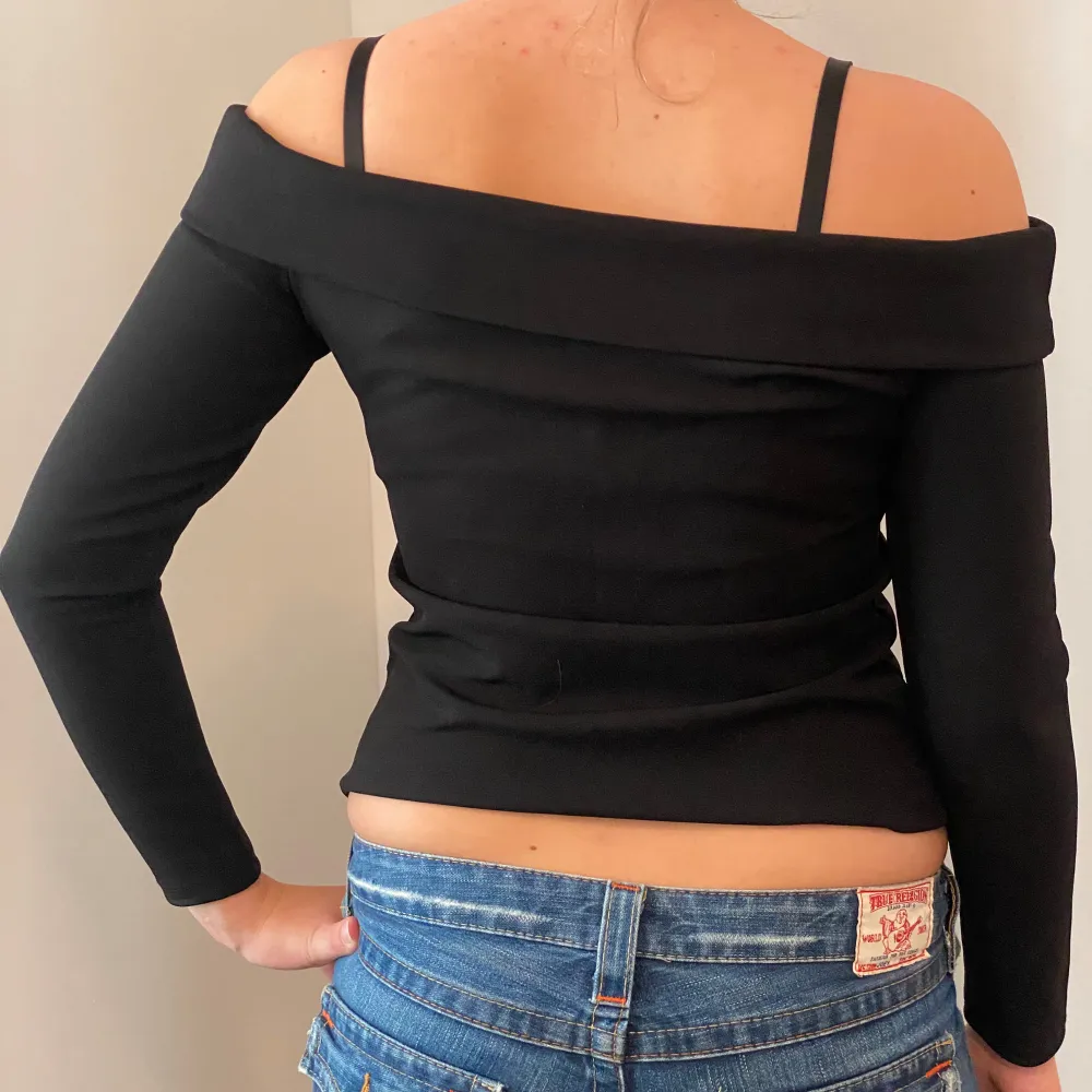 Snygg svart offshoulder topp från H&M i storlek M. Toppen har långa ärmar och smala axelband för en stilren look. Perfekt för både vardag och fest! 🖤. Toppar.