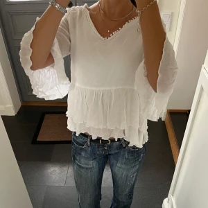 Vit volangtopp - Vit trekvartsärmad volangtopp med knytning från Capri Collection i storlek S.  Använd gärna köp nu!