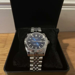 Seiko-modifierad klocka - Vi säljer en stilren Seiko-modifierad klocka som sticker ut från vardagen. Denna klocka har en unik design med noggrant utvalda detaljer som ger den en modern känsla. Länkar ingår, vilket gör att du kan justera storleken för en perfekt passform. 