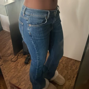 Blå lågmidjade bootcut jeans från Ginatricot - Snygga basic lågmidjade blå bootcut jeans från Ginatricot. De har en klassisk femficksdesign och är tillverkade i ett bekvämt denimtyg. Super sköna och perfekta för en avslappnad stil. 