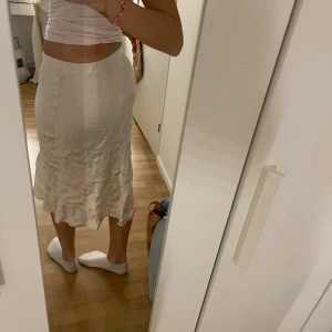 Beige kjol med volang - Snygg beige/ rosa kjol med volangdetaljer i nederkant. Kjolen har en normal passform och är perfekt för sommaren. Den är i siden matrial