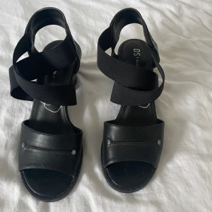 Svarta klackar - Snygga svarta klackar med breda remmar och klack. Perfekta för en stilren look. Klackarna har en bekväm passform och är lätta att matcha med olika outfits.