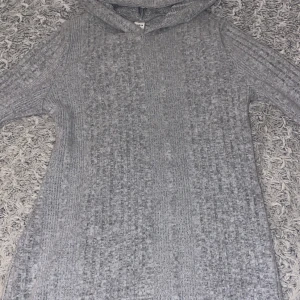 Grå klänning från Shein - Säljer en mysig klänning från Shein. Perfekt för kyliga dagar. Den har en klassisk luva och långa ärmar. Passar perfekt för en avslappnad stil.