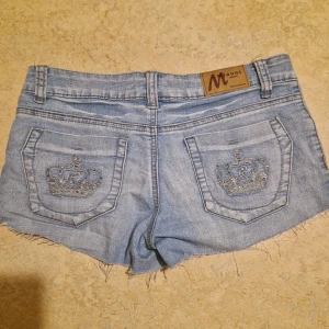 Blå jeansshorts från Miaoni med Coola fickor - Mini lågmidjad jeans shorts kristall kronor på bakfickor och framficka. Från märket miaoni i storlek 30. Den är i bra skick förutom fläckar som inte är synliga. Måtten är: midja=78cm, längd=23, midjehöjd=20cm. Pris kan diskuteras! Skriv om du har några frågor eller vill ha fler bilder!