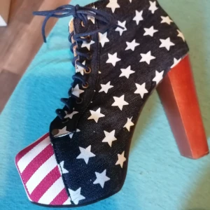 Coola snygga boots  - Unika boots med amerikanskt flaggmönster i rött, vitt och blått. Skorna har en hög klack och snörning framtill. Perfekta för att sticka ut med sin stjärn- och randiga design.
