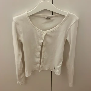 Vit ribbad kofta  - Säljer en stilren vit ribbad kofta. Den har långa ärmar och knappar framtill. Vet inte riktigt storlek då lappen är bort klippt.men storlek 140-146