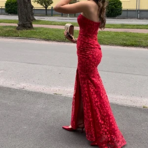 BALKLÄNNING - Elegant röd axelbandslös långklänning med blommigt mönster och slits. Perfekt för bal. Använd 1 gång storlek 36 (S) INKÖPSPRIS: 3459kr säljer för 550kr + frakt 