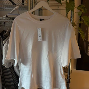 Figursydd t-shirt från Gina Tricot - Säljer en vit t-shirt från Gina Tricot i storlek L. Säljer då den tyvärr inte passade på mig. Helt ny 
