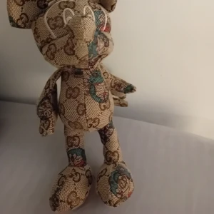 Mönstrad nallebjörn - En unik nallebjörn med ett detaljerat mönster i bruna och beige toner. Den har ett klassiskt designmönster som ger en lyxig känsla. Perfekt som en dekorativ detalj eller en speciell present.