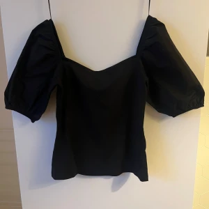 Svart offshoulder topp från H&M - Snygg svart offshoulder topp från H&M med puffiga ärmar. Perfekt för en stilren look. Tillverkad i ett mjukt material som ger en bekväm passform.