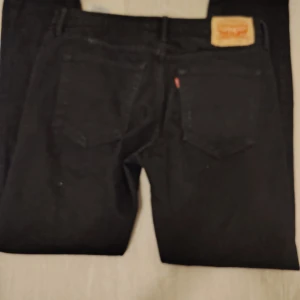 Svarta Levi's 511 jeans - Säljer ett par svarta Levi's 511 jeans. De har en klassisk design med fem fickor och en bekväm passform. Perfekta för en stilren look.