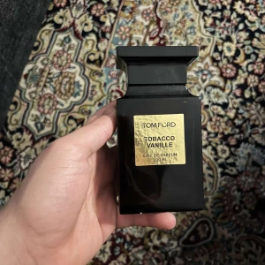 Tom Ford Tobacco Vanille Eau de Parfum - Säljer en lyxig Tom Ford Tobacco Vanille Eau de Parfum i en elegant mörkbrun flaska med guldetikett. Flaskan rymmer 100 ml av denna ikoniska doft som kombinerar rika noter av tobak och vanilj för en varm och kryddig upplevelse. 75 ml är kvar av denna delikatessen.