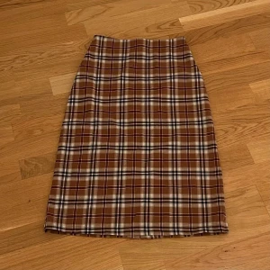 Rutig kjol - Midi-lång kjol från Brandy Melville i brun rutigt mönster. Knappt använd så i nyskick. Storlek är onesize men passar XS bäst.