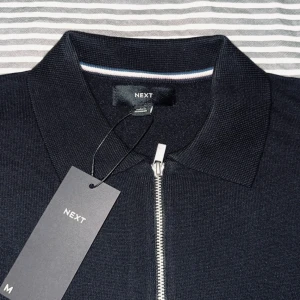 Stickad pikétröja med dragkedja  - Helt ny (aldrig använd), svart pikétröja från Next med dragkedja framtill. Priset går att diskutera.