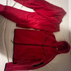 Röd fleecejacka från Nike - Säljer en röd fleecejacka från Nike med dragkedja. Perfekt för kyliga dagar och sportiga aktiviteter. Jackan har en bekväm passform och är långärmad. Storlek L. Pris kan diskuteras vid snabbköp 