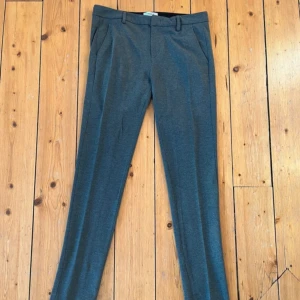 Grå kostymbyxor från Dondup - Snygga grå kostymbyxor från Dondup med dragkedja och knappar. Byxorna har en klassisk straight passform. Storlek i Waist är 32. Perfekt för fest