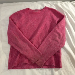 Rosa stickad tröja från Vero Moda - Säljer en mysig rosa stickad tröja från Vero Moda. Tröjan har en rund halsringning och långa ärmar med ribbade muddar. Perfekt för kyligare dagar och ger en avslappnad look. Lite nopprig 