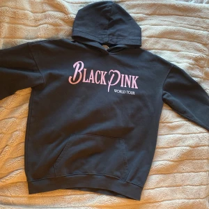 Svart hoodie från H&M x Blackpink - Säljer en snygg svart hoodie från H&M i samarbete med Blackpink. Den har en stor och mysig huva och en praktisk magficka. Texten 'Blackpink World Tour' är tryckt i rosa på framsidan. Perfekt för alla Blackpink-fans! 🖤💗
