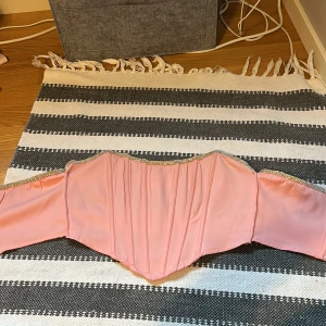 Rosa topp utan axelband - En rosa topp utan axelband med en glittrig kant högst upp från Pretty Little Things. Har sytt in den i sidorna för att den var lite för stor, men der går enkelt att sprätta upp🩷 Skriv gärna vid frågor eller prisförslag🩷