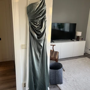 Afton/bal/bröllop/fest klänning  - Säljer denna klänning i storlek 38 passar även storlek 36 och färgen grön, klänningen är i satin med inbyggd korsett. Slits på ena sidan.  Köpte den av en tjej som köpt klänningen i Turkiet hos en skräddare, är för liten på mig därav säljs den vidare