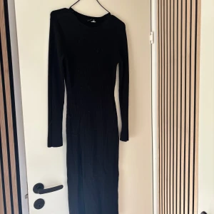 Stickad klänning  -  Stickad klänning med slits fram vid en benet. Nyskick 