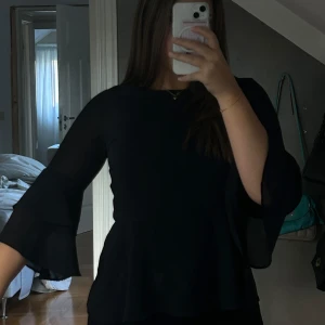 Blus med volang  - Säljer denna super söta svarta blus då den är lite för liten på mig runt armarna. Den har så fin volang på armarna vilket jag älskar och sen är den lite genomskinlig så då kan man antingen ha linne under ( som ja har på bilden ) eller bara bh. Som ny