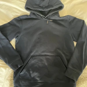Mörkblå hoodie med tryck - Säljer en snygg mörkblå hoodie med ett coolt 'Mi Amor'-tryck på ryggen. Köpt för cirka 1200kr och använd ett fåtal gånger. Säljer på grund av att den inte kommer till användning.