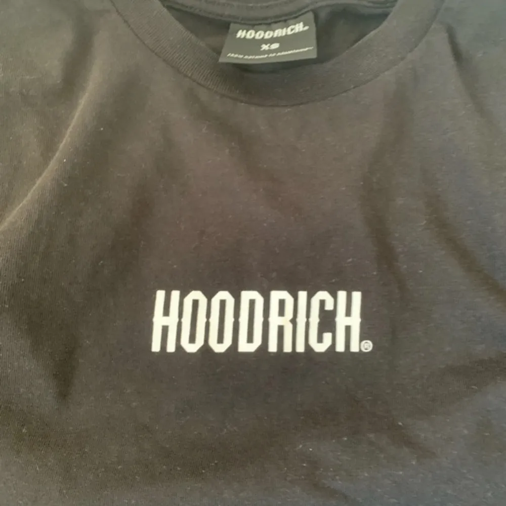 Säljer en svart t-shirt från Hoodrich i storlek XS. Den har en enkel och stilren design med 'HOODRICH' tryckt i vitt på bröstet. Perfekt för en casual look!. T-shirts.