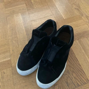 Eytys Doja S-O Sneaker - Snygga svarta sneakers i mocka med en lila detalj på hälen och vit sula. Perfekta för en stilren look. Original box tillkommer