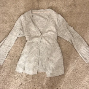 Grå kofta från Cappuccini - Hollister liknade babydoll grå kofta från Cappuccini med en enkel knapp framtill. Den har en ribbad design nedtill och långa ärmar. Perfekt för kyliga dagar. Storlek står ej men skulle säga att den är typ M/L