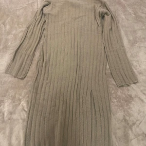 Stickad klänning  - Brun/beige maxi stickad klänning med slits ifrån nelly i storlek M. Klänningen är stor i storlek. Aldrig haft tillfället att ha på mig klänningen. 