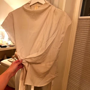 Beige blus från cider med knyt - Snygg beige blus med knyt i midjan och korta ärmar. Perfekt för en stilren look. Helt oanvänd!