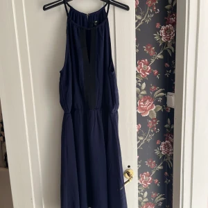 Mörkblå ärmlös klänning - Snygg mörkblå klänning med ärmlös design och smala axelband. Perfekt för sommarens alla tillfällen. Klänningen har en elegant passform och ett lätt, flödande tyg.